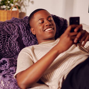 Young man holding cellphone with both hands looking closely at the screen