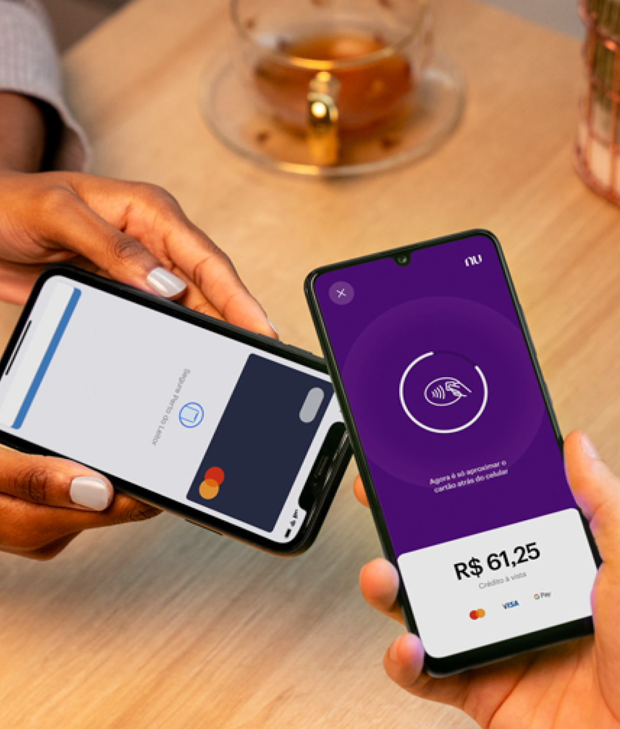 Uma mão segurando um celular enquanto outra aproxima outro celular com sua carteira digital