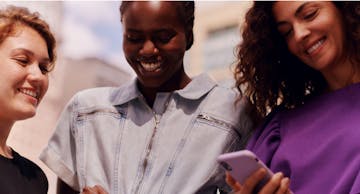 image of three women smiling while looking at a phone screen