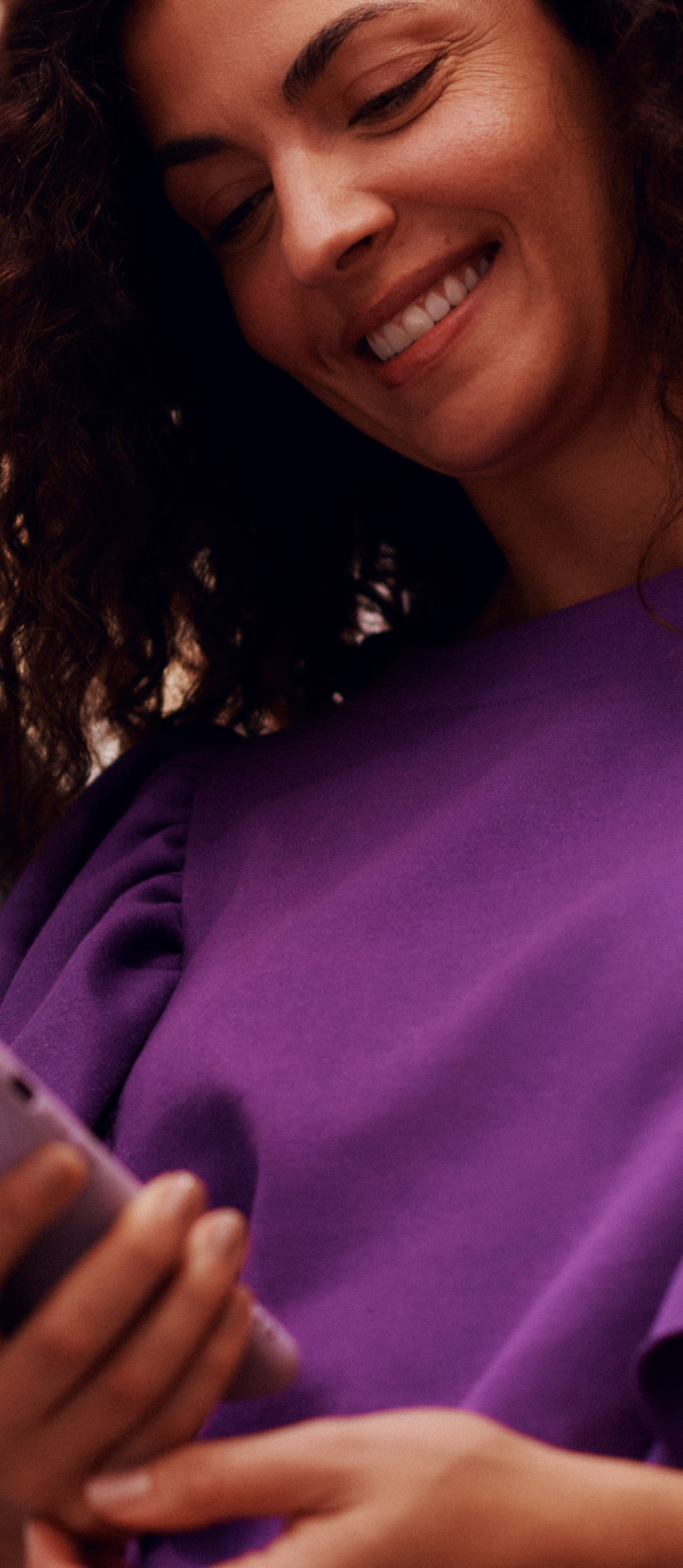 Imagem de uma mulher sorrindo enquanto segura o cartão do Nubank próximo ao rosto.