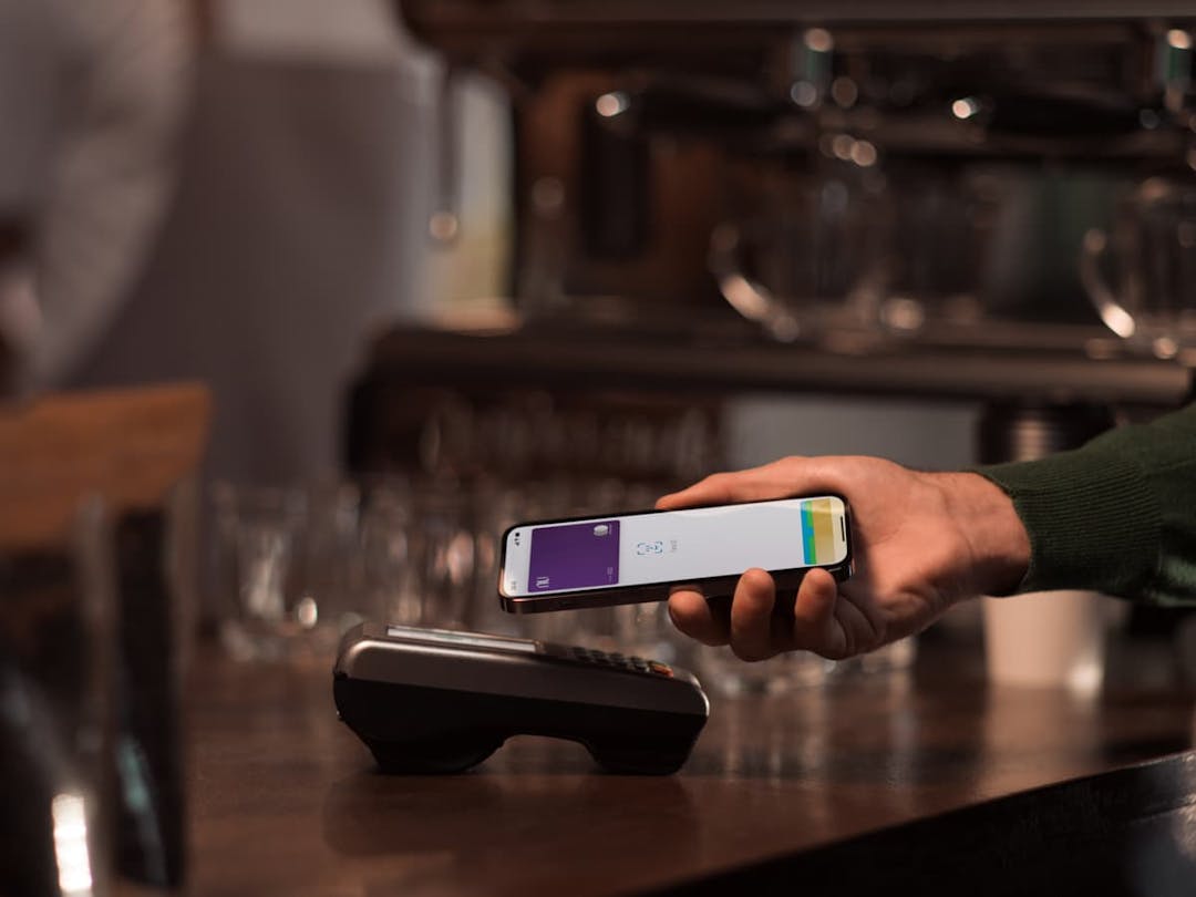 foto de uma pessoa segurando seu celular e pagando por aproximação a conta de um restaurante