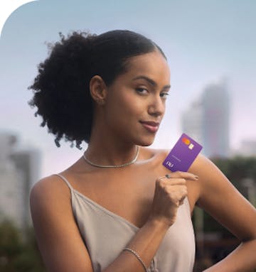 Imagem de uma mulher segurando o cartão do nubank em um ambiente aberto