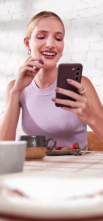 mulher comendo cerejas olhando para o celular