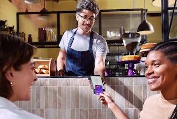 Duas mulheres pagando por aproximação em uma cafeteria