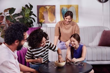 Uma família na sala de estar montando um quebra-cabeça