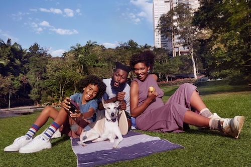 Familia sentada no parque com cachorro.