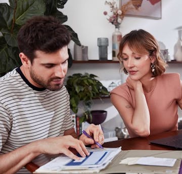 Casal em uma mesa analisando papéis